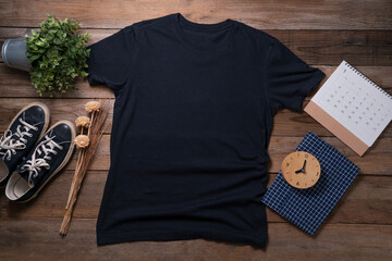 Mockup of a black t-shirt blank shirt template with accessories on the wooden table background,...