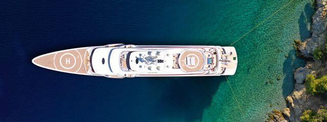 Aerial drone ultra wide top down photo of luxury exotic yacht with wooden deck and helipad anchored...