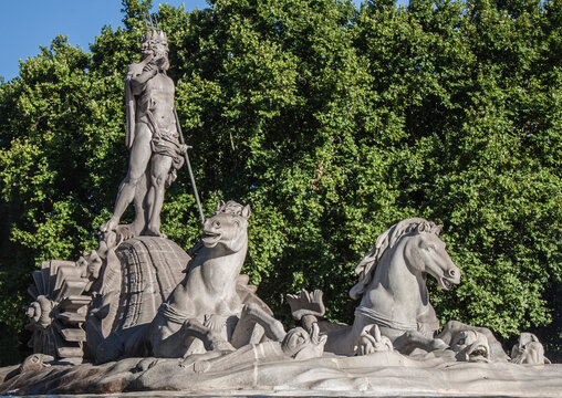 Fountain of Neptune in the old town of Madrid, Spain. The statue shows the god of the sea, with a trident in one hand and a coiled snake in the other, surrounded by dolphins and two sea horses.
