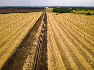 Open oil pipeline exposed that is under construction on agricultural field. Aerial view