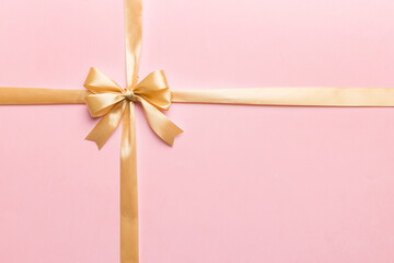 Top view of gold ribbon rolled and yellowbow isolated on colored background. Flat lay with copy space