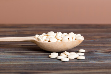 Heap of white pills on colored background. Tablets scattered on a table. Pile of red soft gelatin capsule. Vitamins and dietary supplements concept