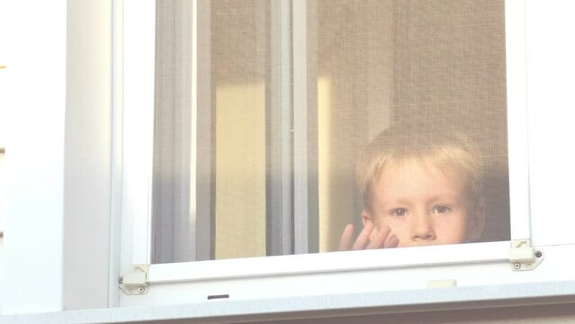 Happy boy meets parents at the open window, he happily waving his hands and smiling. Child in home isolation while world virus pandemic - Powered by Adobe