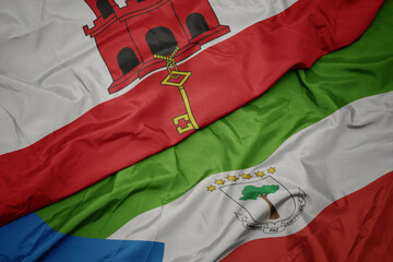 waving colorful flag of equatorial guinea and national flag of gibraltar.