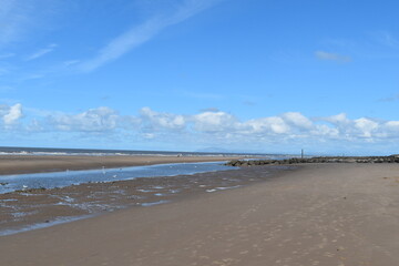 Dramatic cloudy sky over the sea with waves crashing onto the beach. Taken in Fleetwood Lancashire England. 