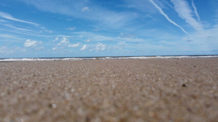 Low angle view of the beach with waves crashing and a blue sky background. Taken in Fleetwood Lancashire England. 
