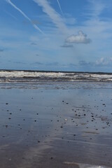 Fototapeta premium Dramatic cloudy sky over the sea with waves crashing onto the beach. Taken in Fleetwood Lancashire England. 