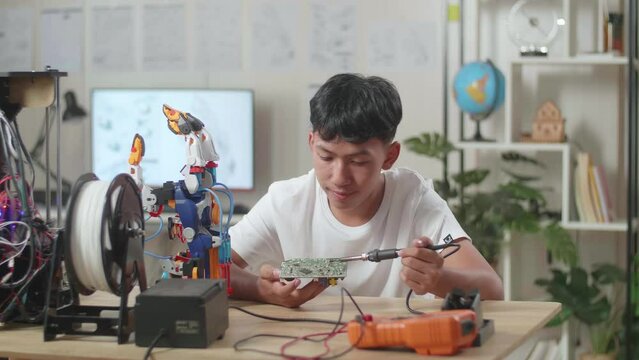 Asian Boy Holding And Fixing The Circuit Board While Repairing A Cyborg Hand At Home
