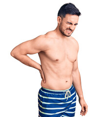 Fototapeta premium Young handsome man wearing swimwear suffering of backache, touching back with hand, muscular pain