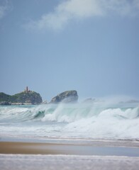 Relaxing view of the ocean waves splashing on the sand under the blue sky