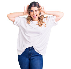 Fototapeta premium Young caucasian woman wearing casual clothes smiling cheerful playing peek a boo with hands showing face. surprised and exited