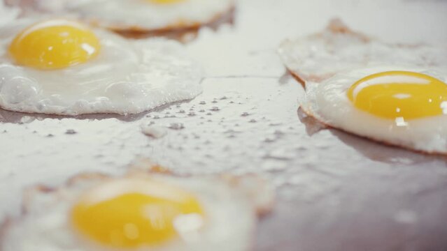 Closeup shot of a person cracking an egg over a pan with eggs