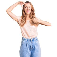 Fototapeta premium Young beautiful caucasian woman with blond hair wearing casual clothes smiling making frame with hands and fingers with happy face. creativity and photography concept.