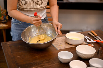 A female whisking her softened butter, sugar, eggs and flour together in the mixing bowl.