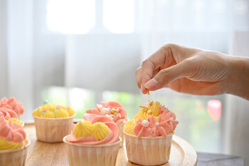 Cupcake with woman hand decorating the cupcake in the kitchen