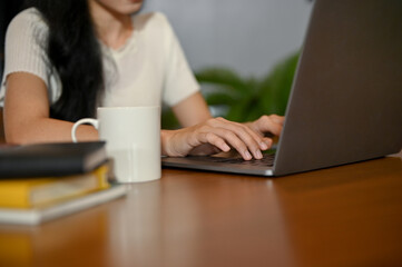 cropped, A pretty Asian female typing on notebook keyboard, using laptop.