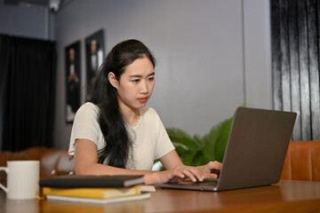 Attractive young Asian female college student using laptop computer