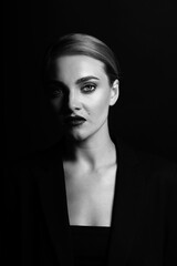 Fashion, style, business and make-up concept. Black and white studio portrait of beautiful and sexy looking blonde woman looking to camera. Model with classic hairstyle and wearing black suit