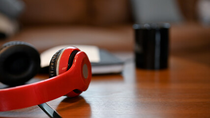 A modern red wireless headphones is on the wood table. Technology concept.