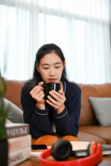 Portrait, Pretty asian female sipping morning coffee while relaxing in her living room.