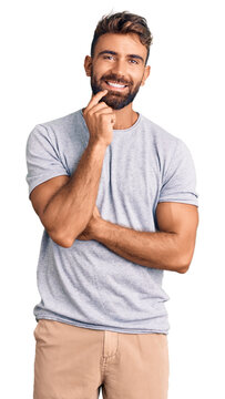 Young hispanic man wearing casual clothes looking confident at the camera smiling with crossed arms and hand raised on chin. thinking positive.