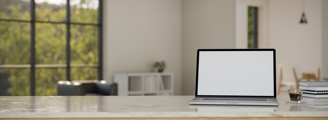 Marble workspace tabletop with laptop mockup and copy space over blurred white living room
