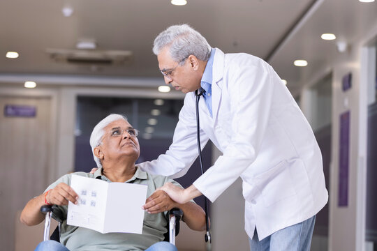 Doctors comforting disabled elderly patient in wheelchair at hospital
