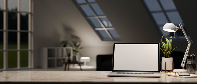 Marble working table with laptop mockup, table lamp and copy space over blurred dark living room