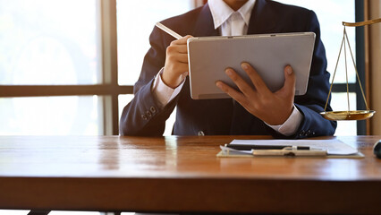 Smart male lawyer or business legal consultant using digital tablet, working at his desk.