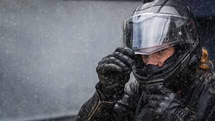 Biker puts a motorcycle helmet on his head in winter, copy space