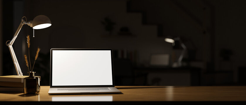 Modern dark home workspace at night with light from table lamp, notebook laptop mockup