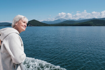 Fototapeta na wymiar Senior caucasian woman with gray hair on boat trip. Lake Baikal, Russia.