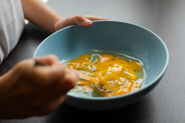 mixing egg yolks in a blue bowl