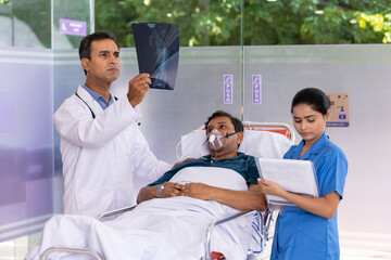 Nurse with male doctor examining x-ray report of patient lying on stretcher bed at hospital
