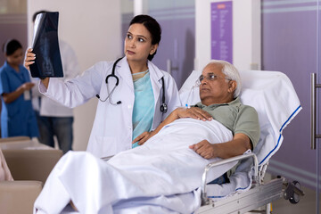 Obraz premium Female doctor examining x-ray report of patient lying on stretcher bed at hospital 