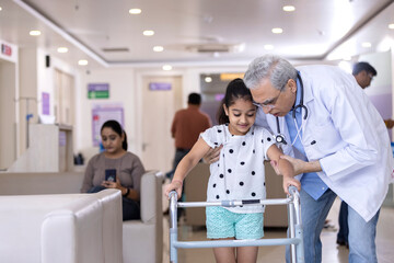 Male doctor teaching disabled girl to use walker at hospital
