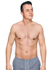 Fototapeta premium Handsome young man wearing swimwear shirtless smiling looking to the side and staring away thinking.