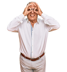 Senior caucasian man wearing business shirt and glasses doing ok gesture like binoculars sticking tongue out, eyes looking through fingers. crazy expression.