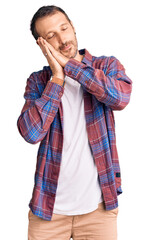 Young handsome man wearing casual clothes sleeping tired dreaming and posing with hands together while smiling with closed eyes.