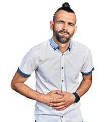 Hispanic man with ponytail wearing casual white shirt with hand on stomach because indigestion,...