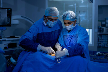 Two doctor surgeons operating patient at hospital 
