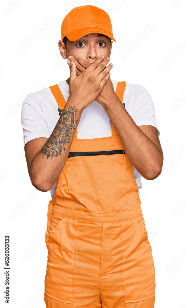 Canvas Prints Young handsome african american man wearing handyman uniform shocked covering mouth with hands for mistake. secret concept.