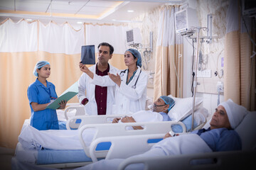Doctor examining senior patient in critical health conditions and examining the x ray in the intensive care unit
