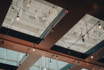 Toned photo colorful light bulb string on ceiling near glass roof and wooden exposure beam structure of terminal airport bar in Houston, Texas, USA