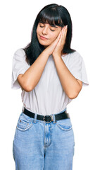Obraz premium Young hispanic girl wearing casual clothes sleeping tired dreaming and posing with hands together while smiling with closed eyes.