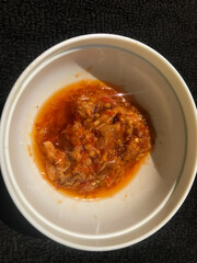 The pulverized sauce on a pink plastic bowl isolated on a dark background