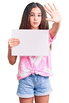 Cute Hispanic Child Girl Holding Blank Empty Banner With Open Hand Doing Stop Sign With Serious And Confident Expression, Defense Gesture