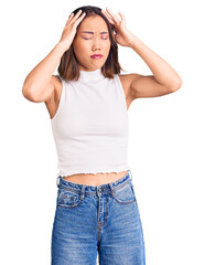 Young beautiful chinese girl wearing casual clothes suffering from headache desperate and stressed because pain and migraine. hands on head.