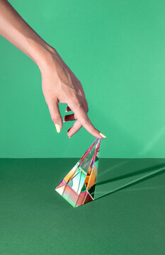 Minimal abstract concept with hand pushing a reflective glass prism on green background. Gambling, casino games, poker lux aesthetic. Money, surreal, retro futurism holographic cripto  crystal idea.