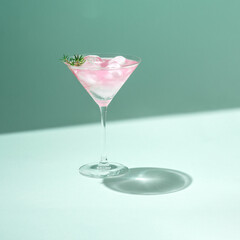 Tropical cold drink cocktail minimal concept with pastel pink martini glass and ice on green color...